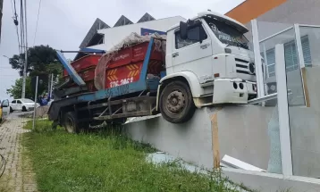 IMAGENS: Caminhão desgovernado desce rua, bate em carro, invade imóvel e fica preso em muro